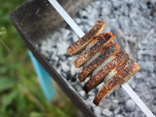 Asar carne y pan en una brocheta sobre el brasero.