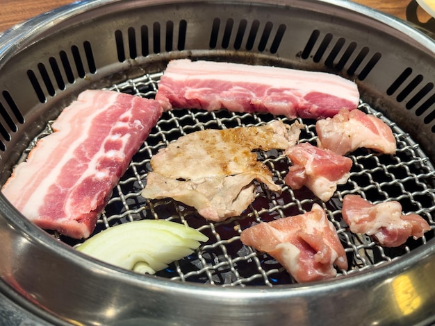 Asar carne de panceta de cerdo en una red redonda de barbacoa en un restaurante para comer
