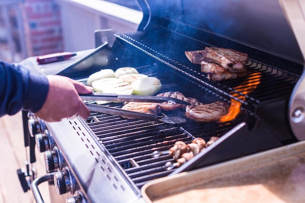 Asar chuletas de cerdo en parrilla de gas en verano.