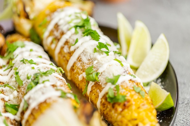 Asar elote de maíz callejero mexicano adornado con especias y cilantro fresco en un plato para servir.