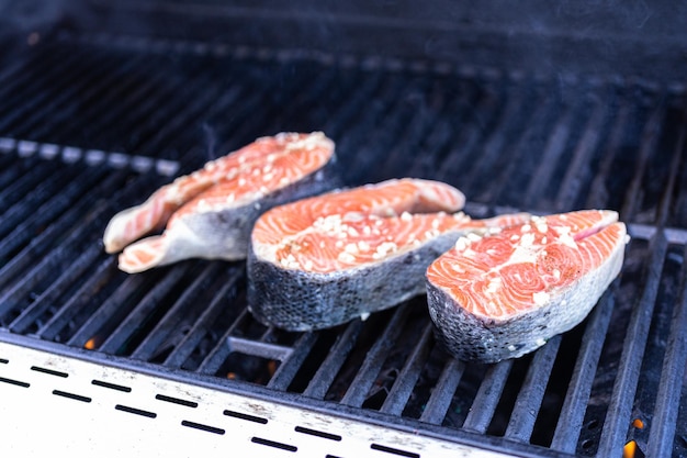 Asar filetes de salmón en una parrilla de gas al aire libre.