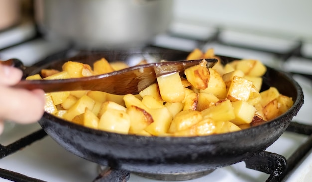 Asar papas frescas en una sartén de hierro fundido con aceite de girasol Una vista de una estufa con una fritura