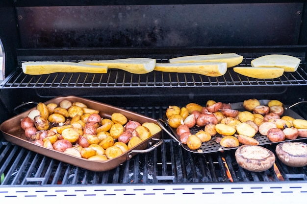 Asar patatas pequeñas con rodajas de ajo en una parrilla de gas al aire libre.