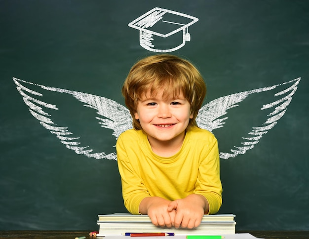 Asas da escola e sonho feliz escola crianças conceito de escola sala de aula garotinho engraçado apontando para cima no bl ...