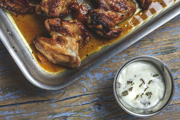 Asas de frango assadas caseiras na assadeira na mesa de madeira