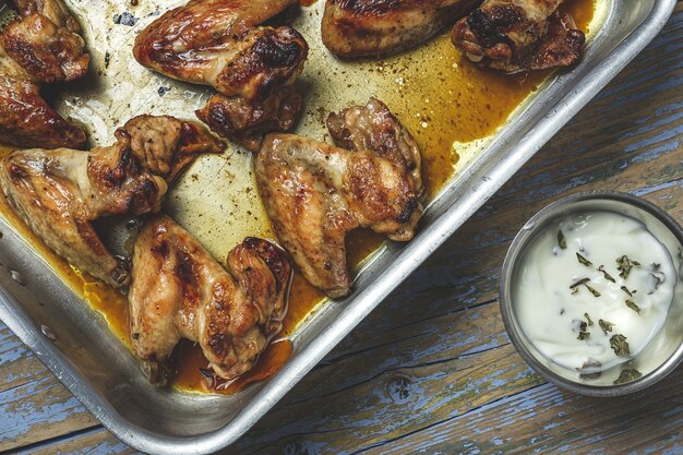 Asas de frango assadas caseiras na assadeira na mesa de madeira