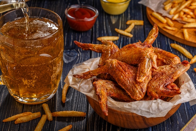 Asas de frango com batatas fritas e cerveja.