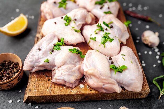 asas de frango cru em uma tábua com temperos em um fundo de pedra