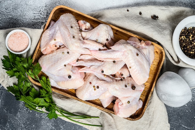 Asas de frango cru em uma tigela de madeira. Vista do topo