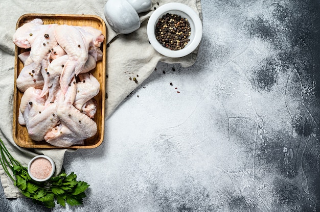 Asas de frango cru. Exploração avícola orgânica. Vista do topo. Fundo cinza. Espaço para texto