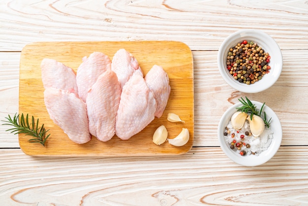 Asas de frango cru fresco médio na placa de madeira