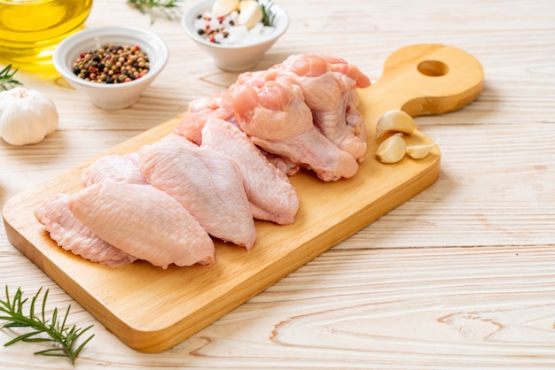 Asas de frango cru fresco na placa de madeira