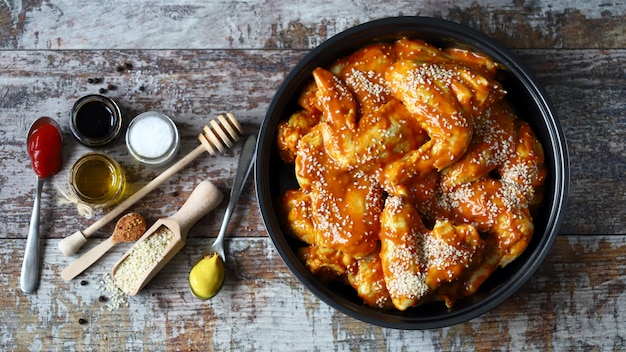 Asas de frango cru marinado em uma frigideira antes de cozinhar. Cozinhar asas de frango. Receita de asas de búfalo. Keto Paleo. Pegan.