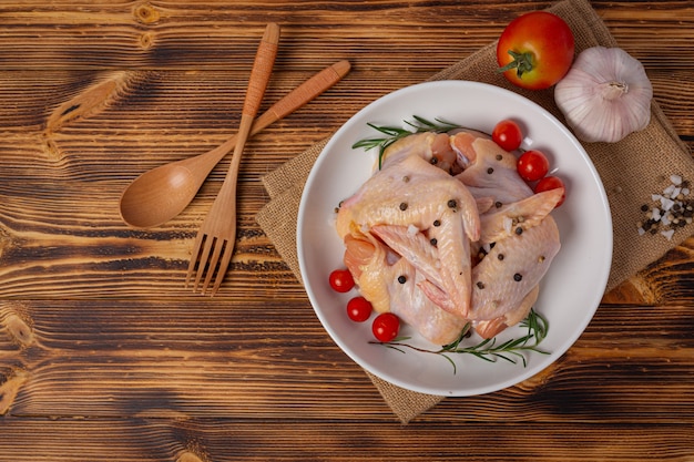 Asas de frango cru na superfície de madeira escura.