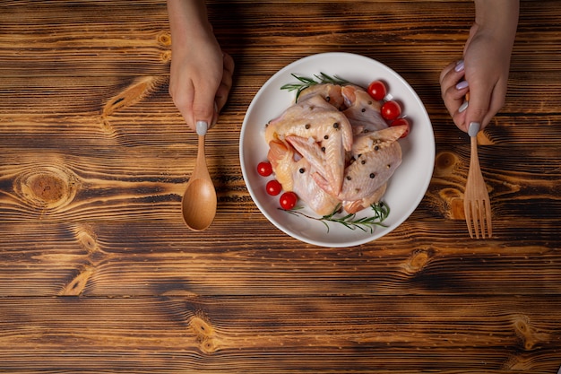 Asas de frango cru na superfície de madeira escura.