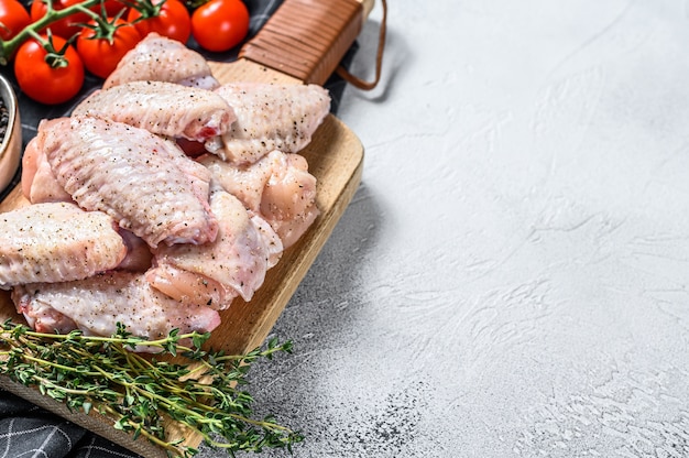 Asas de frango cru na tábua, carne de frango orgânica. Fundo branco. Vista do topo. Copie o espaço