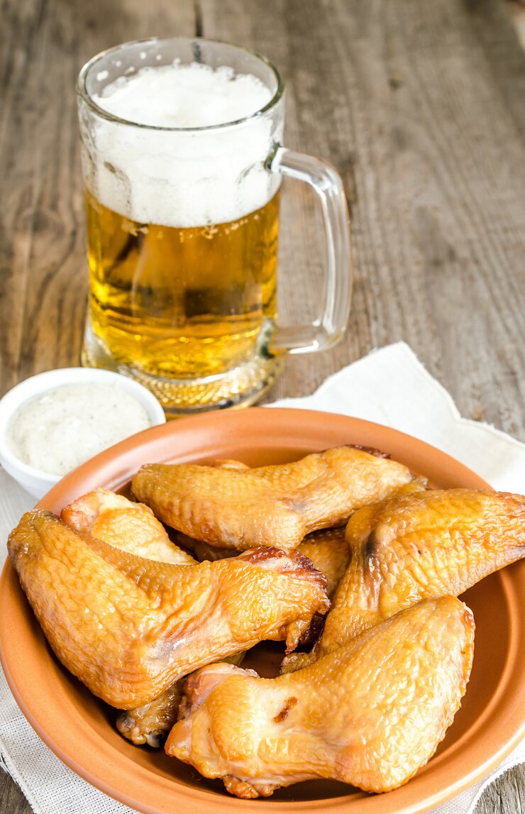 Foto asas de frango defumado com molho picante e copo de cerveja
