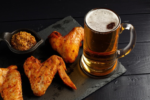 Asas de frango e cerveja Comida farta e saborosa Prato de deliciosas asas de frango de churrasco