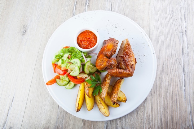 Asas de frango frito com salada de batata frita e molho picante