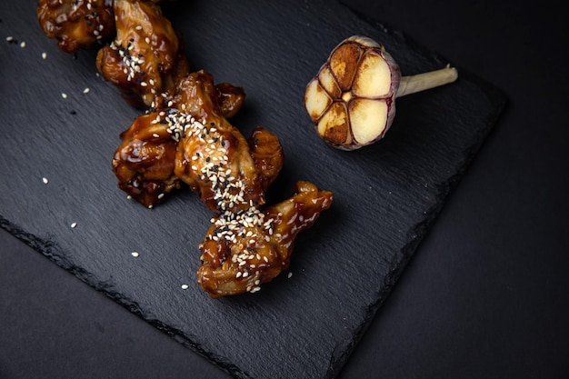 asas de frango frito com sementes de gergelim e especiarias em fundo preto