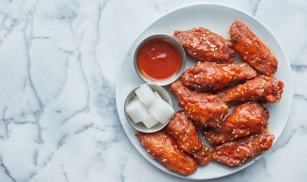 Asas de frango frito coreano ao molho gochujang com rabanete em conserva e kimchi