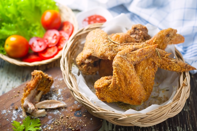 Asas de frango frito e ketchup em fundo de madeira