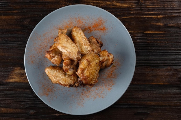 Asas de frango frito em um prato sobre uma mesa de madeira