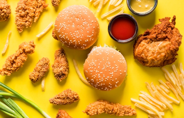 Asas de frango frito, hambúrgueres e batatas fritas com molhos de cima