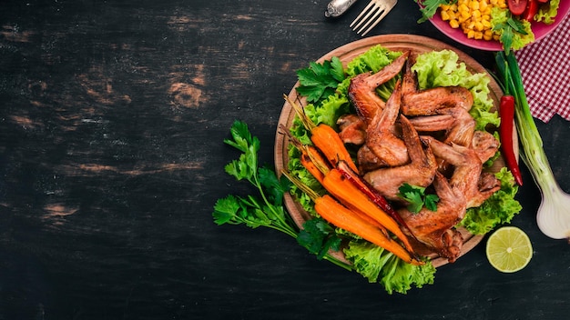 Asas de frango grelhadas com legumes e cenouras em um fundo de madeira vista superior Copiar espaço