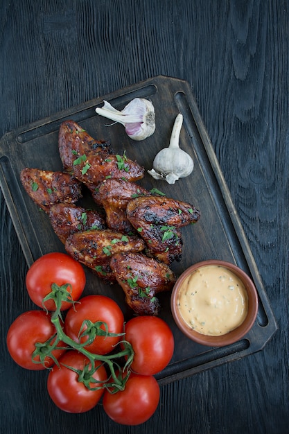 Asas de frango grelhado com molho e ervas.