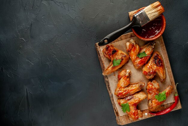 Asas de frango grelhado em molho barbecue com salsa em uma tábua sobre uma mesa de concreto. Vista do topo . com espaço de cópia para o seu texto
