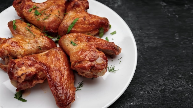 Asas de frango grelhado em um prato em um fundo escuro