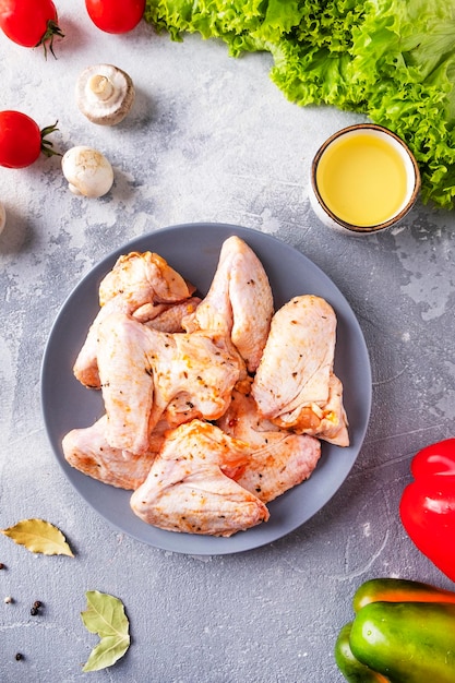 Asas de frango marinado cru em um prato vista superior