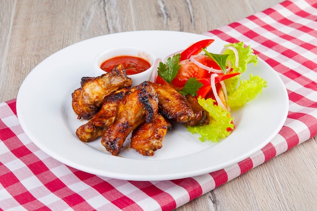 Foto asas de frango para churrasco com molho vermelho e vegetais