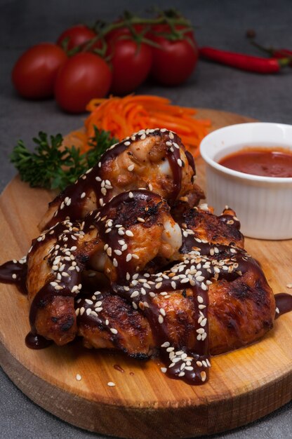 Asas de frango quente com molho de tomate em uma placa de madeira