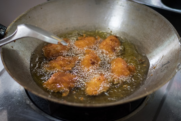 Asas de frango são fritas em uma panela.