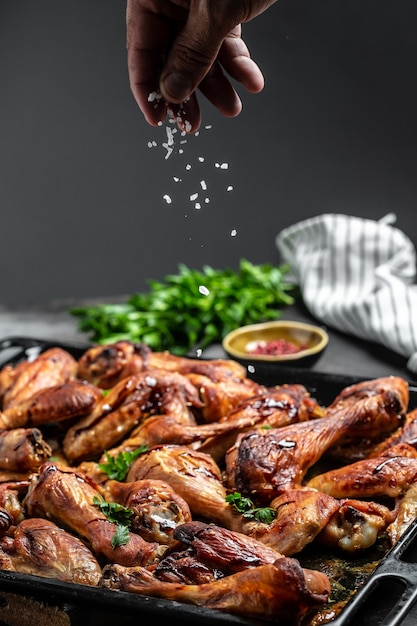 Asas e pernas de frango quentes com aipo, cook mão polvilhando salada com carne em um movimento de congelamento. fundo de receita de comida. fechar-se.