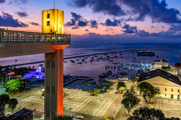 El ascensor Lacerda iluminado al anochecer y con el mar y los barcos en la ciudad de Salvador Bahia