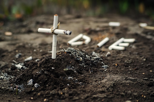 Aschenbecher mit Asche und Zigarette sehen aus wie Grab und Kreuz