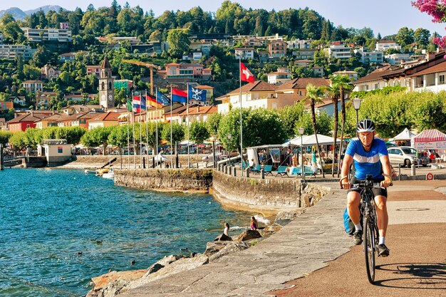 Ascona, Suiza - 23 de agosto de 2016: Hombre montando una bicicleta en el paseo marítimo del lujoso resort en Ascona en el lago Maggiore en el cantón de Ticino en Suiza.