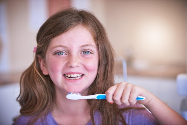 Asegurándome de que mis blancos nacarados se mantengan nacarados Captura recortada de una niña pequeña cepillándose los dientes