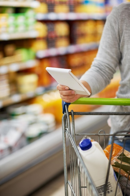 Asegurándose de que obtenga todo lo que necesita Primer plano de una mujer revisando su lista de compras en una tienda de comestibles