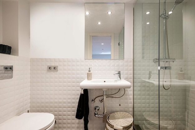 Aseo con ducha y mampara de cristal lavabo blanco mimbre cesto de ropa espejo rectangular y toallero colgante