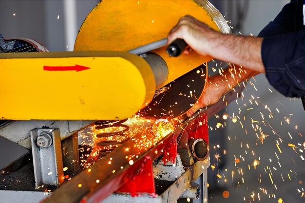 Aserrado de metal en el taller en el sitio de producción con una máquina estacionaria Sierra circular eléctrica para metal