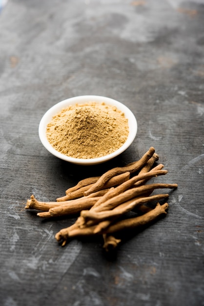 Foto ashwagandha ou aswaganda ou ginseng indiano é um medicamento ayurveda em forma de caule e pó. isolado em fundo liso. foco seletivo