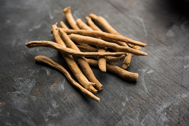 Foto ashwagandha ou aswaganda ou ginseng indiano é um medicamento ayurveda em forma de caule e pó. isolado em fundo liso. foco seletivo