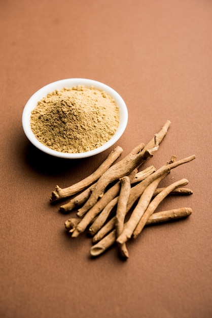 Ashwagandha ou aswaganda ou ginseng indiano é um medicamento ayurveda em forma de caule e pó. isolado em fundo liso. foco seletivo