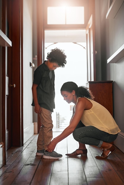 Y así es como se atan los cordones de los zapatos Foto de una mujer atando los cordones de sus hijos