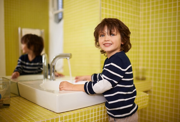 Así es como mamá me enseñó a hacerlo Un lindo niño lavándose las manos en el lavabo del baño