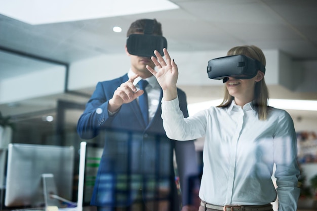 Así es como se ve el futuro de los negocios Toma de exposición múltiple de dos compañeros de trabajo haciendo una lluvia de ideas juntos en la oficina mientras usan auriculares VR